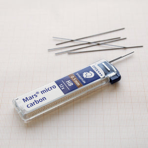 Open Mars micro carbon 0.5 mm HB tube lying on grid paper with several leads spilled out beside it