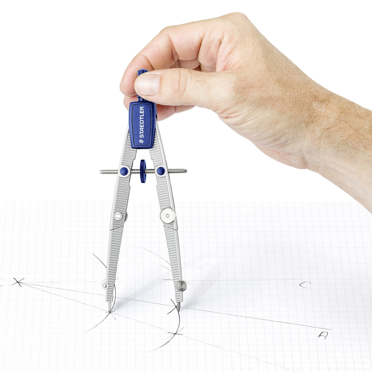 A hand turning the Staedtler Noris 550 01 compass to draw arcs on squared paper with construction marks