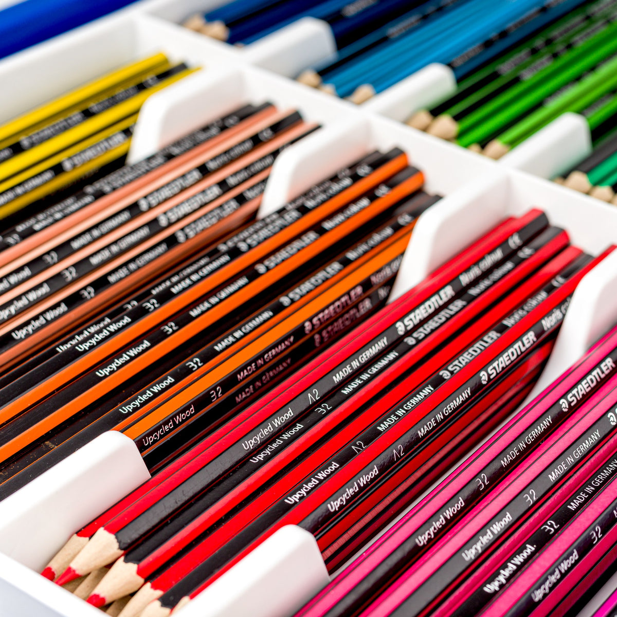 Close view inside the tray: Noris colour pencils grouped by colour in white divided compartments, red, orange, green and blue rows