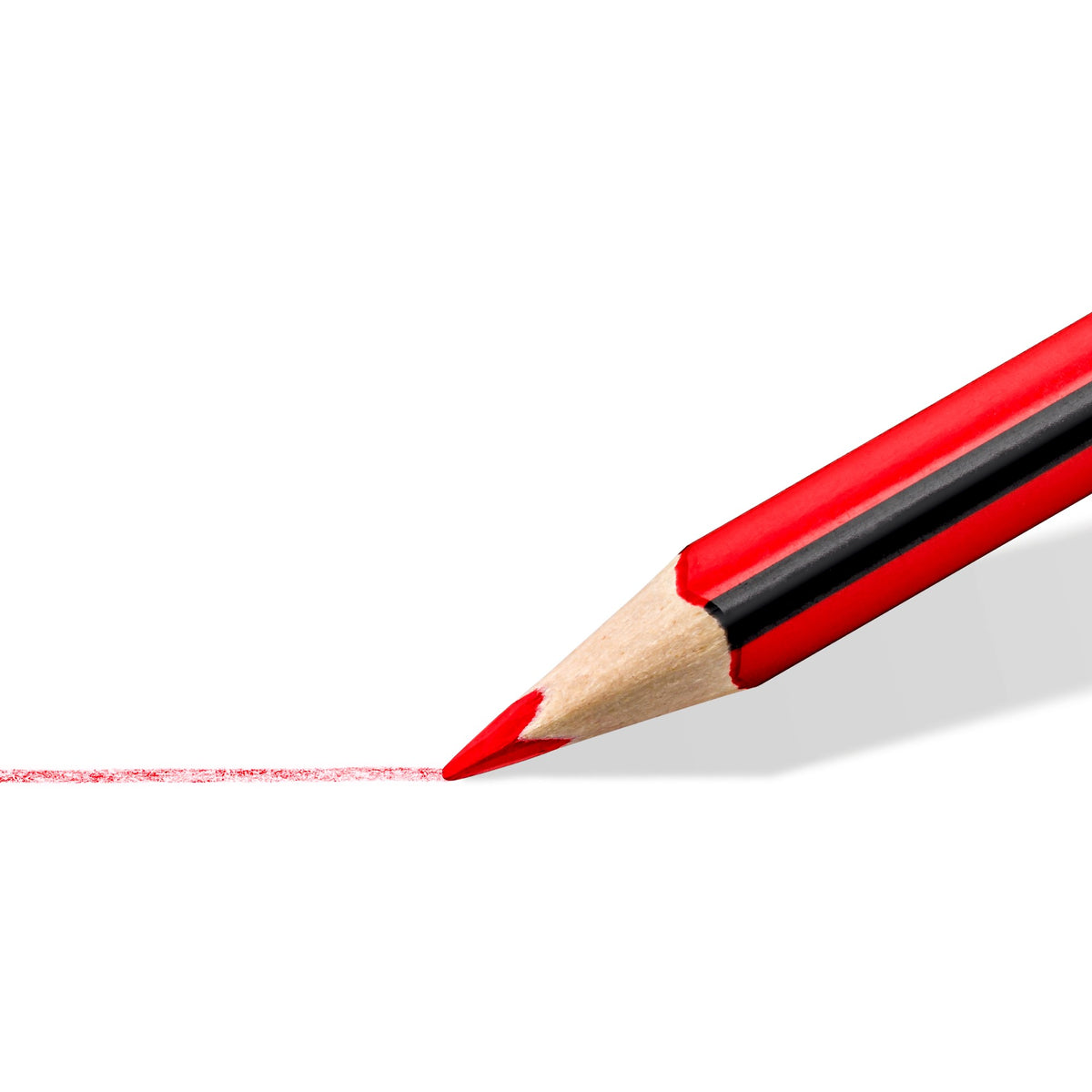 Sharpened red triangular pencil tip close up drawing a light red line on white paper