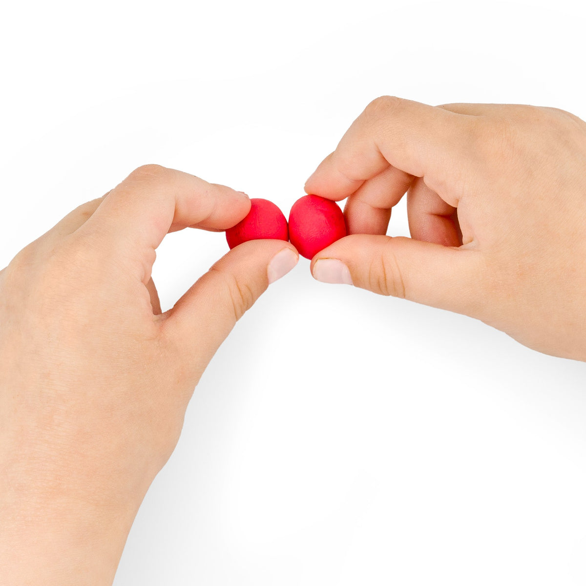 Fingers pressing two small red balls of Noris junior modelling dough together