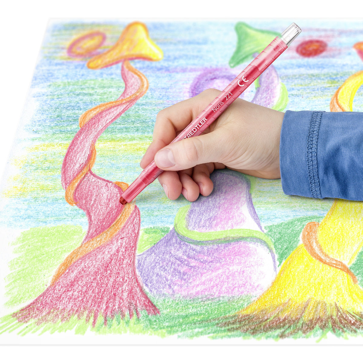 Child colouring a fantasy landscape of trees and hills with a red Noris wax twister
