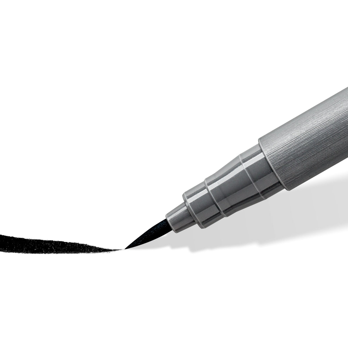Close view of a Staedtler 372 soft brush tip drawing a tapering black stroke; the range photo shows the intense black pen