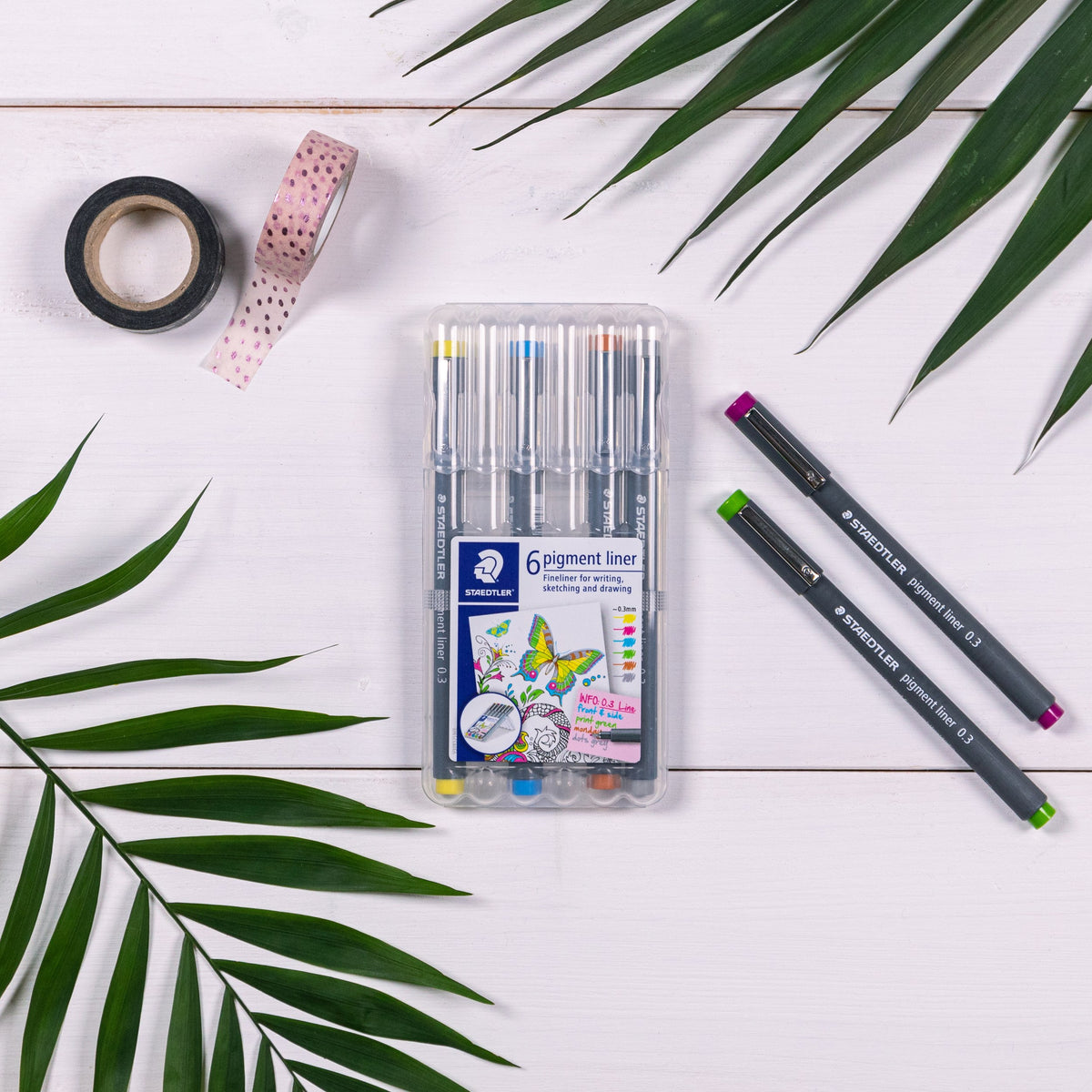 Staedtler photo of the six-colour 0.3 mm pigment liner wallet on white boards with two loose liners, palm leaves and washi tape