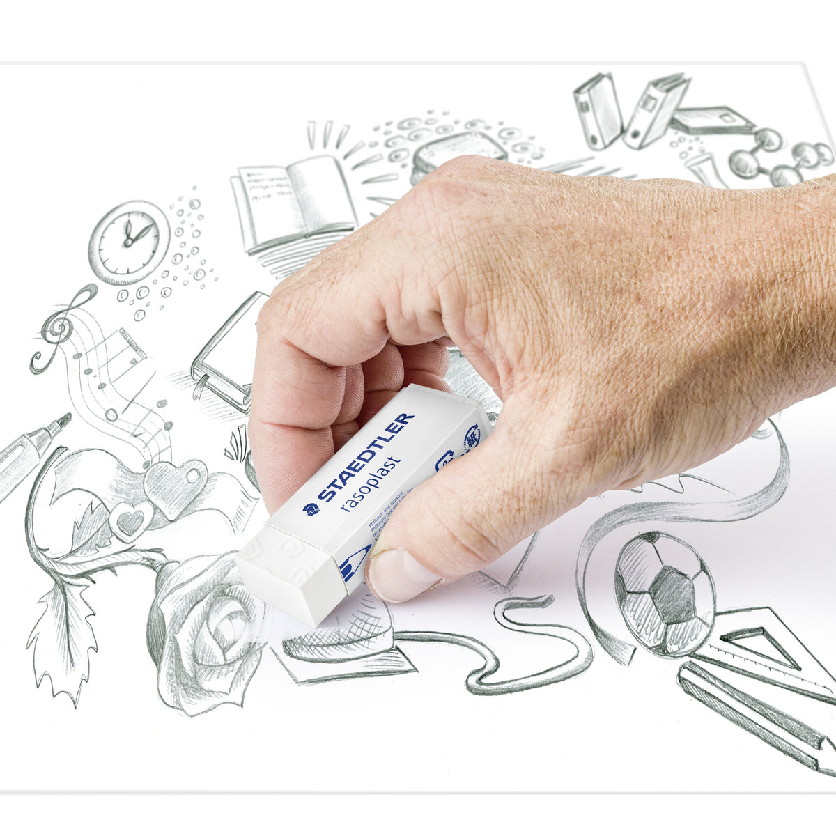 Staedtler rasoplast eraser held between thumb and fingers above a pencil drawing of a rose and music notes