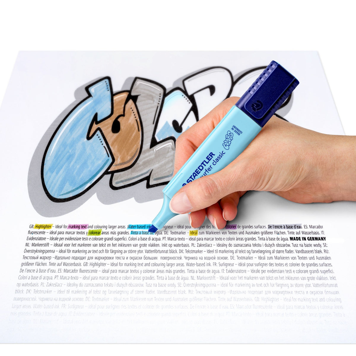 Staedtler range image of a hand shading COLORS lettering with a sky blue pastel Textsurfer classic on printed text