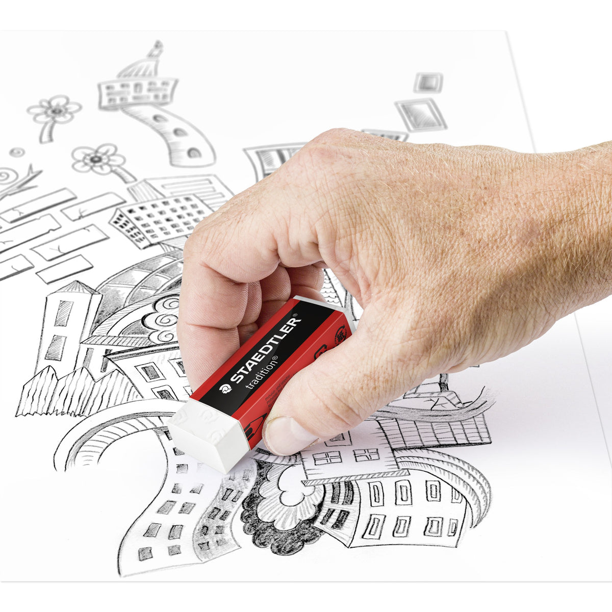 Hand rubbing out pencil lines with a tradition eraser on a drawing of old town buildings