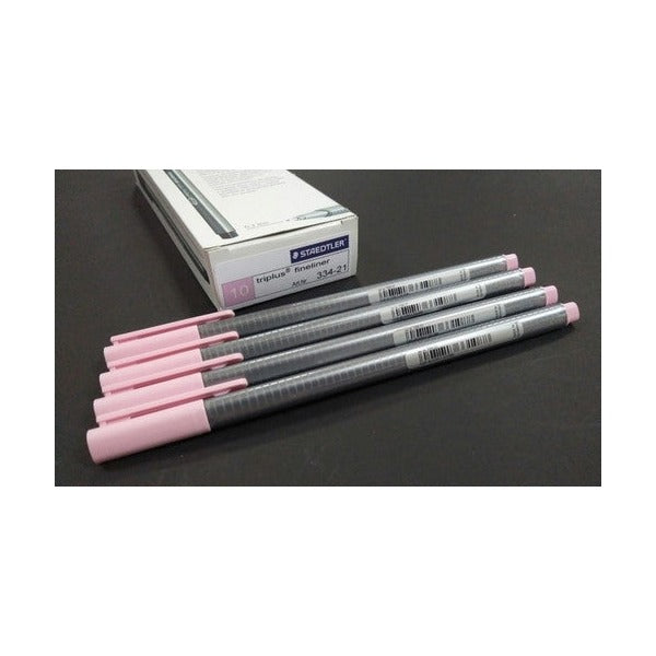 Four pale pink triplus fineliners on a dark surface in front of a white Staedtler box printed 10 and 334-21
