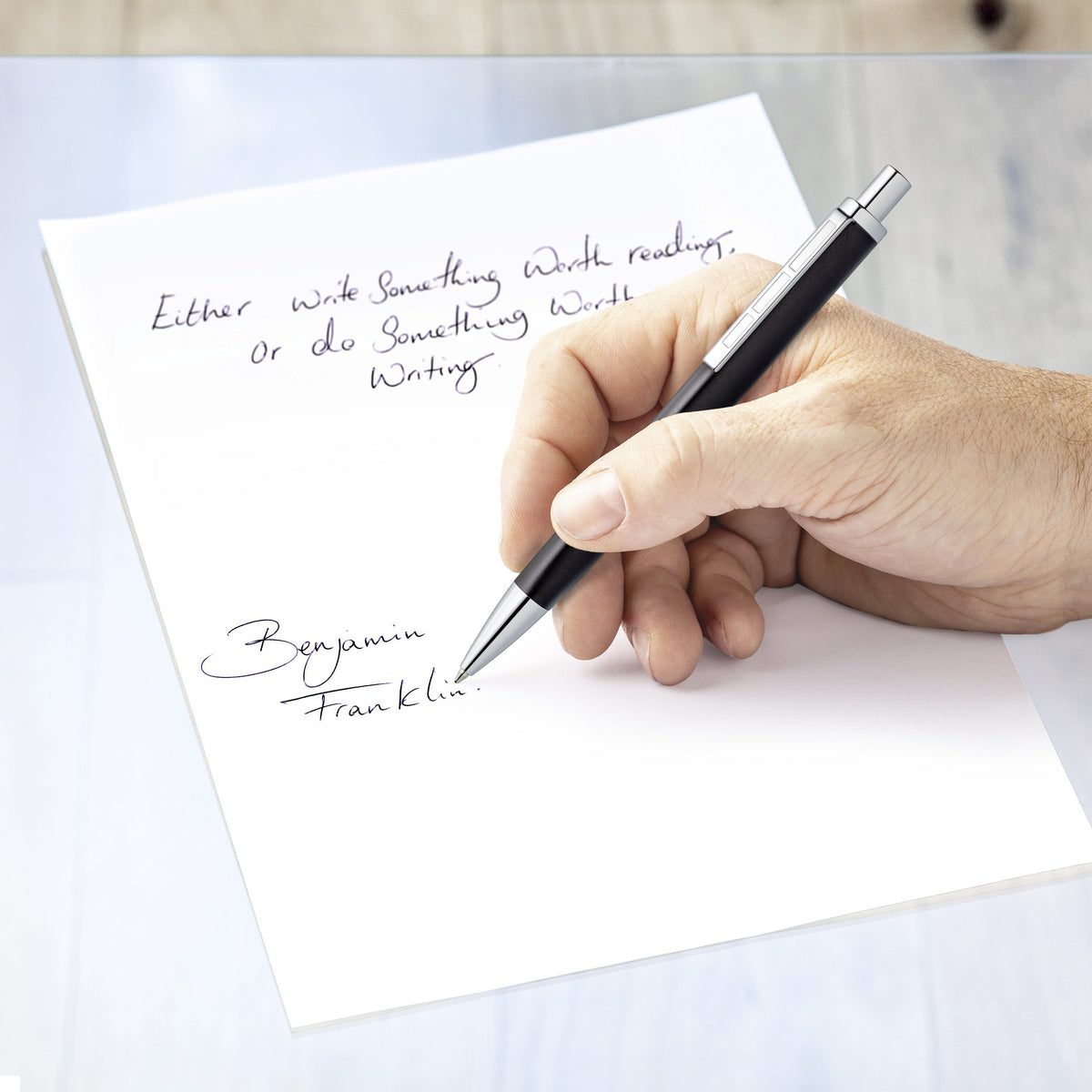 Hand writing in blue with the anthracite triplus ballpoint on white paper, ending with a Benjamin Franklin signature