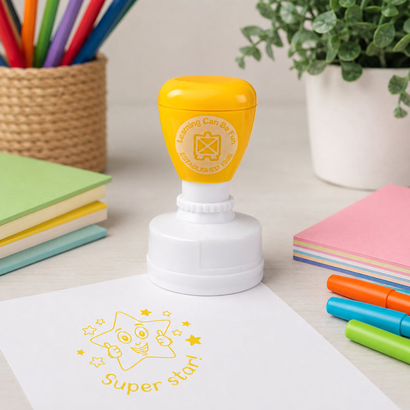 Yellow self inking Super Star Merit Stamp shown in a bright classroom setup with colourful books, markers and stationery. The clear star impression highlights its use for encouraging students and celebrating progress.