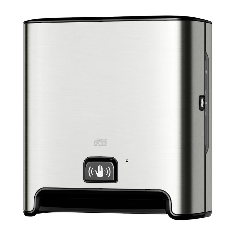 Brushed stainless steel Tork hand towel dispenser with a black base trim and a push button on the lower front panel