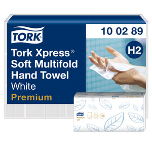 Wrapped bulk pack of Tork Xpress Soft Multifold Hand Towel in white and navy livery, code 10 02 89 and H2 badge, photo of hands drying on the label, with a single blue leaf printed towel sleeve in front.