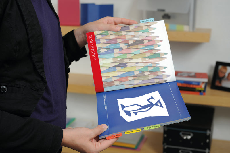 3L twin tabs in red, yellow and green along the lower edge of a book held open in an office