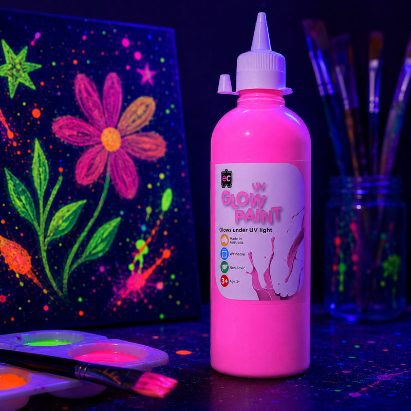 Close up of Educational Colours UV Glow Paint 500ml Pink beside fluorescent flower artwork glowing brightly under blacklight conditions.