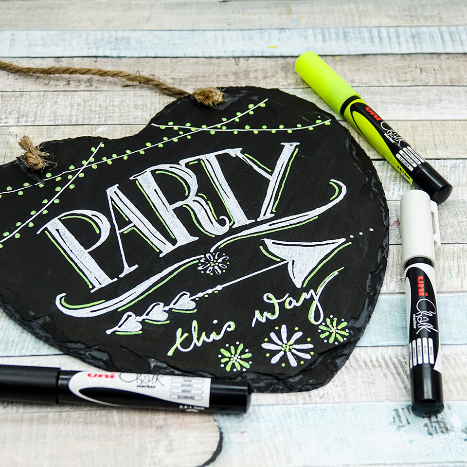Slate party sign hand lettered in white and fluorescent yellow chalk marker, PWE-3MS pens alongside