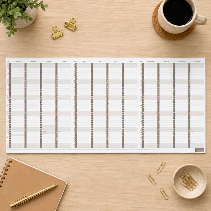Top view of the Upward 2027 A4 Fold Out Paper Planner fully opened across a clean workspace with stationery, coffee and notebooks. The planner provides a convenient year to view layout while remaining compact enough to fold to A4 size for storage and travel.
