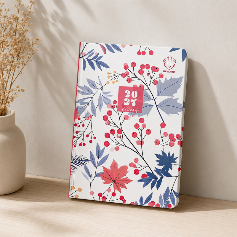 The Upward Fashion 2027 A5 Hardcover Week To Opening Diary displayed upright against a softly lit neutral wall, emphasising the sophisticated floral Begonia cover, durable hardcover construction and elegant design suitable for professional and personal planning.