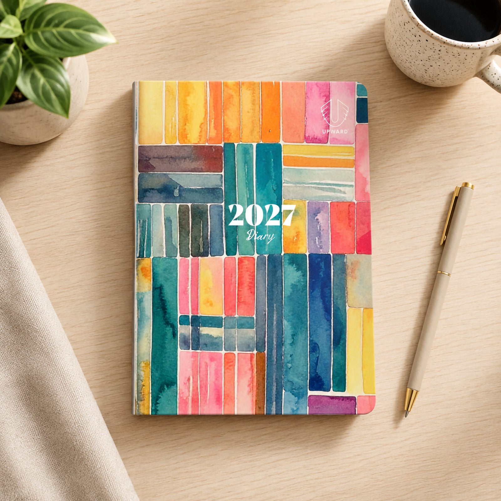 Overhead view of the diary closed on a desk showcasing the colourful Printed Stripe watercolour design. The vibrant combination of blue, pink, orange and yellow tones creates a creative and modern appearance suitable for personal and professional use.