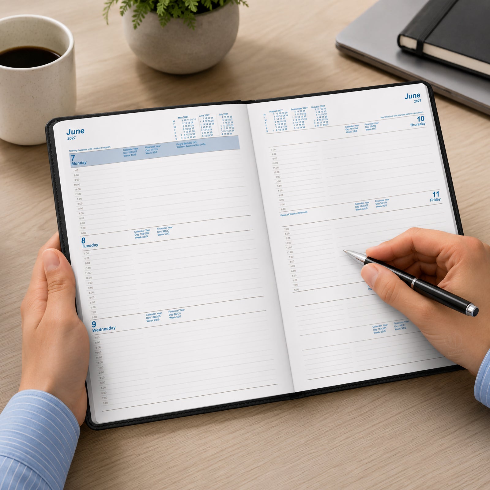 A user writes in the Upward Standard 2027 A5 Week To View Diary opened across a desk workspace. The weekly layout provides generous writing space for appointments, meetings and daily planning, making it ideal for professionals managing busy schedules throughout the year.