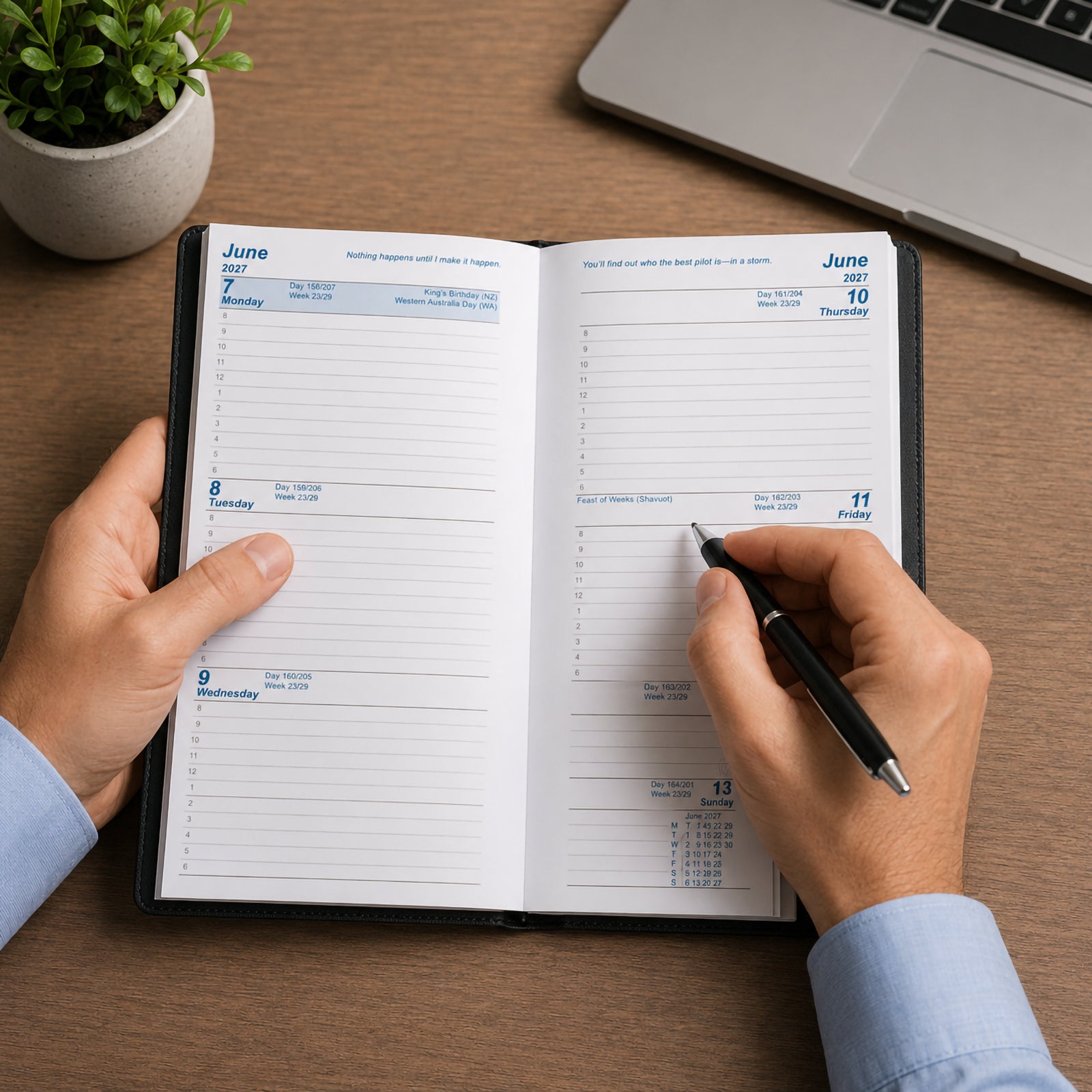 A professional uses the Upward Standard 2027 A6/7 Week To View Diary at a desk beside a laptop and indoor plant. The open weekly layout displays each day clearly across the spread, providing ample writing space for appointments, schedules, reminders and daily planning throughout the week.