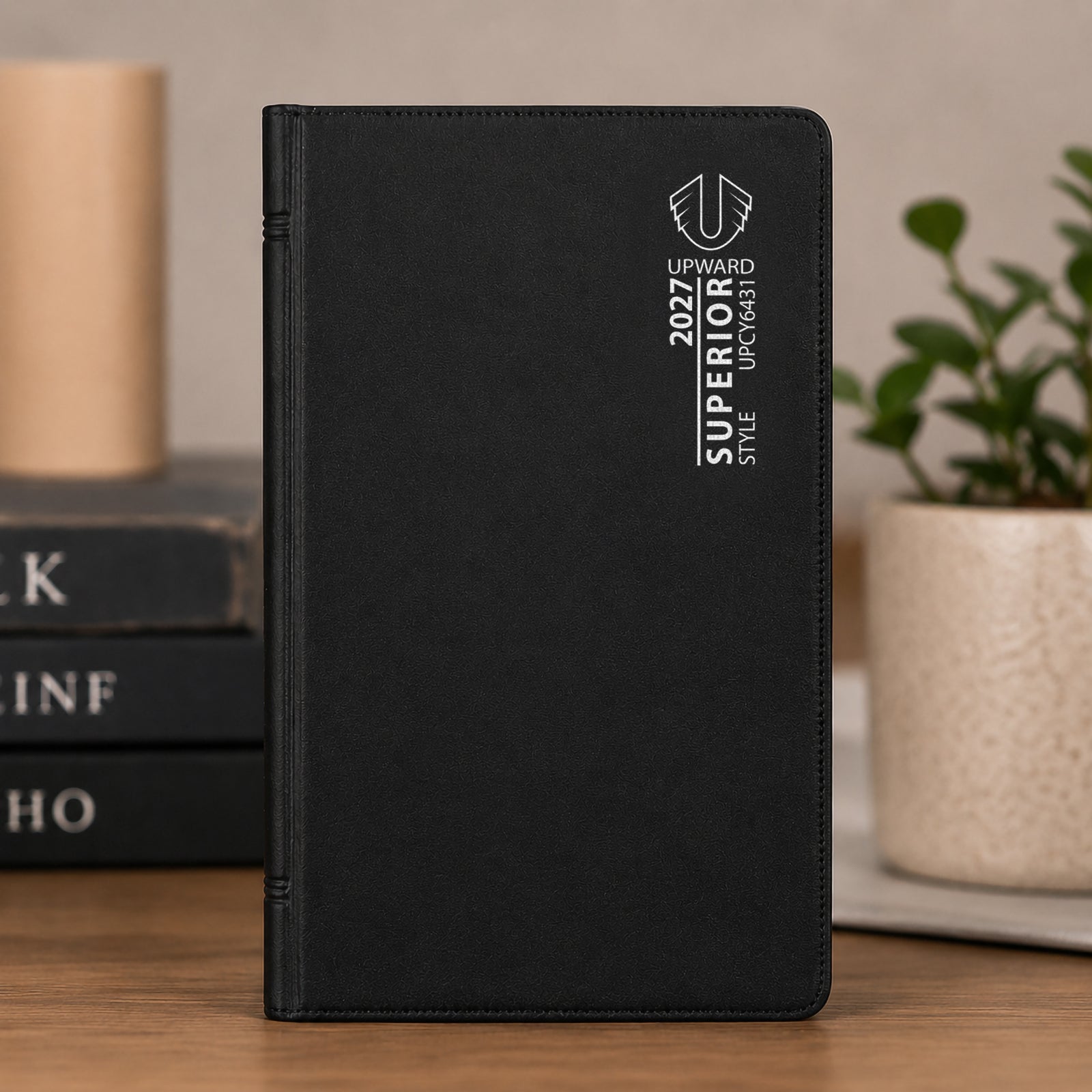 Front cover view of the Upward Superior 2027 diary standing upright in a workspace setting. The sleek black finish and professional branding demonstrate its suitability for business professionals and organised planners.