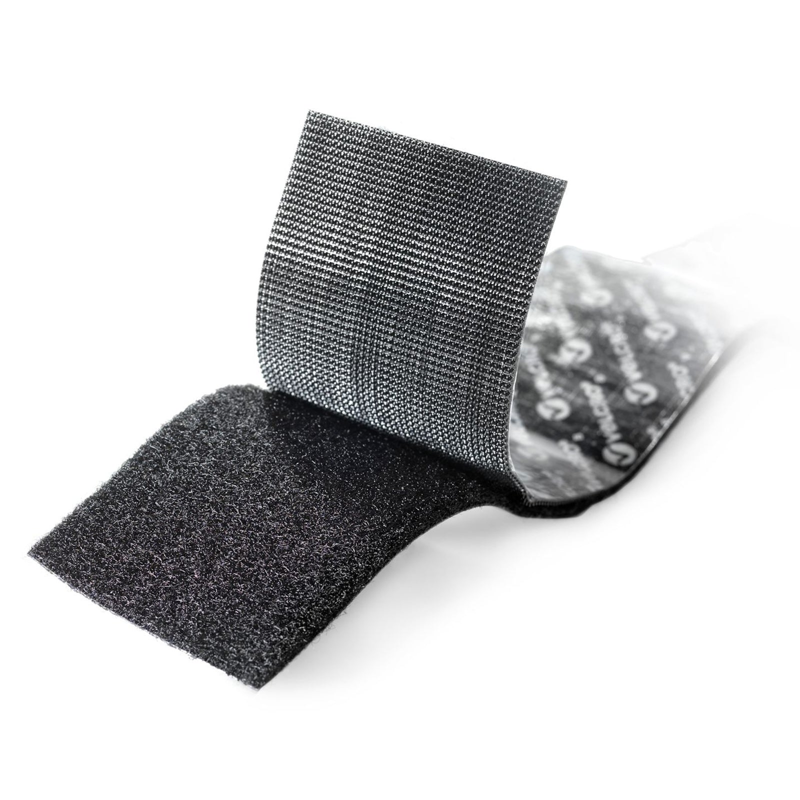 Close up photograph of black VELCRO Brand heavy duty hook and loop tape separated to display both hook and loop fastening surfaces with strong adhesive backing designed for industrial strength applications.