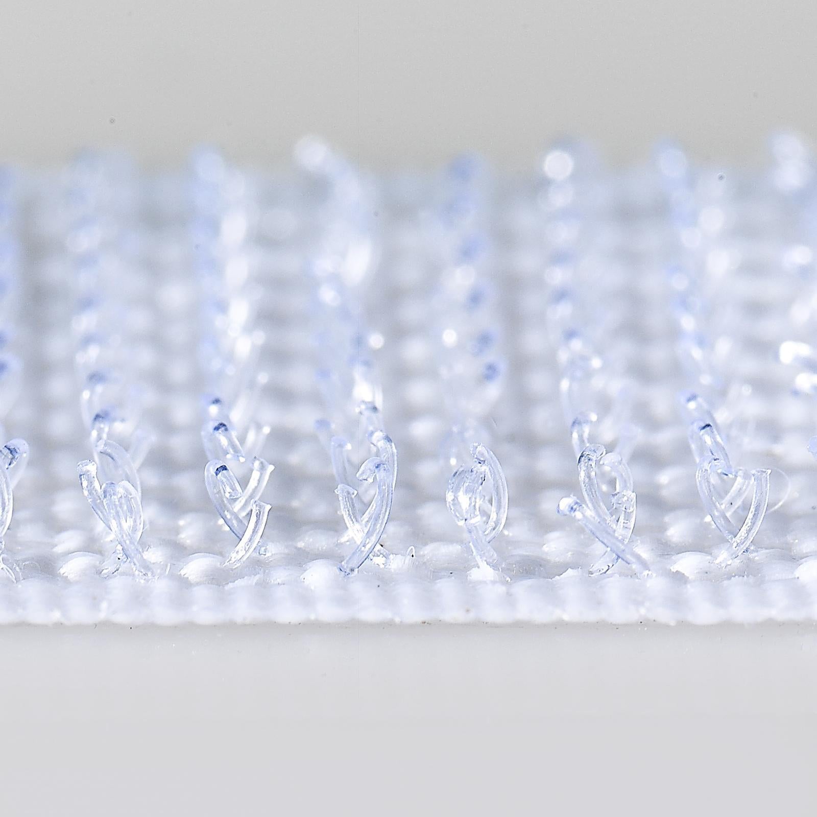 Extreme close up photograph of transparent white VELCRO Brand hook fasteners showing detailed hook texture designed for strong reusable indoor fastening.
