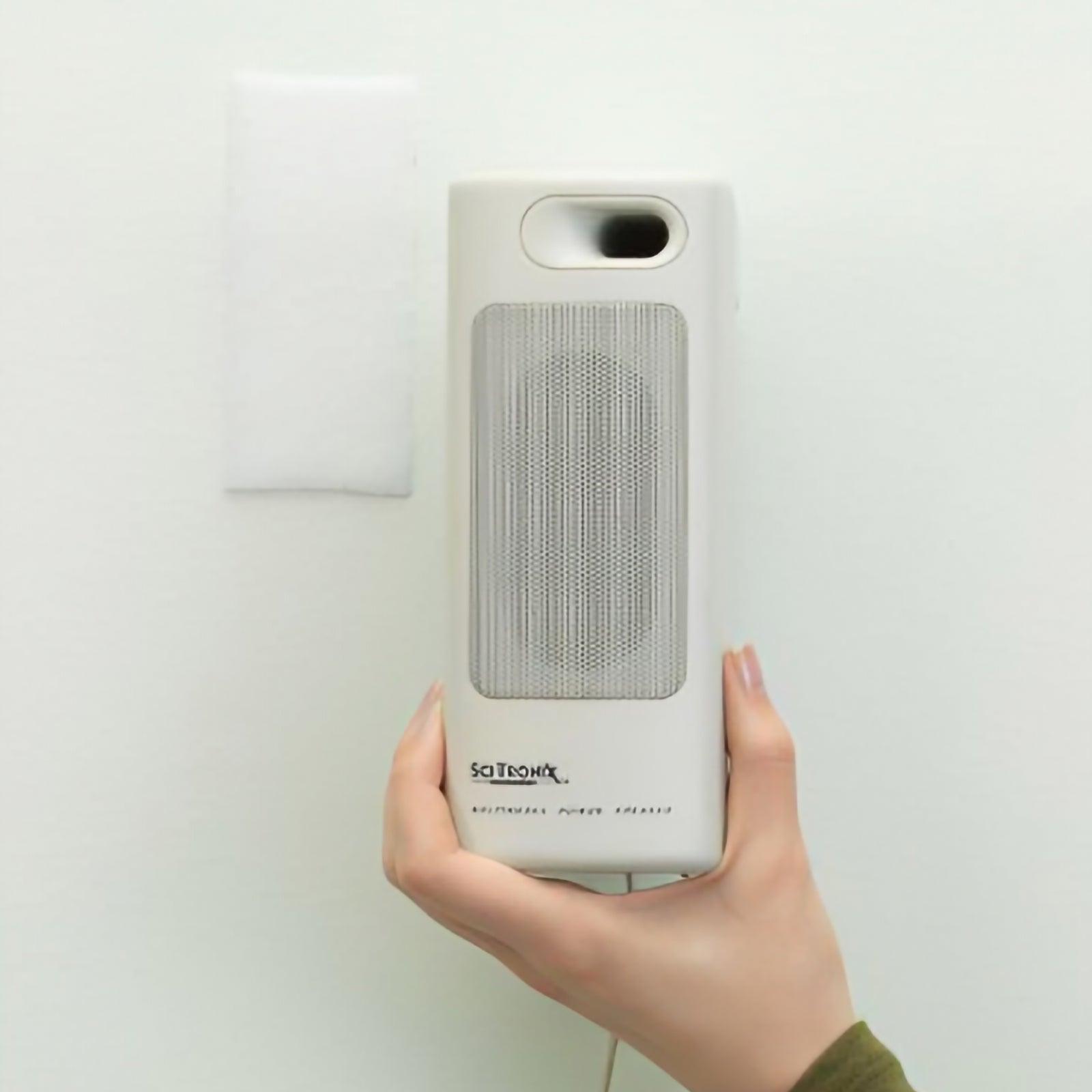 White VELCRO Brand hook and loop tape attached to a wall holding a lightweight speaker remote accessory neatly in place for organised indoor storage.