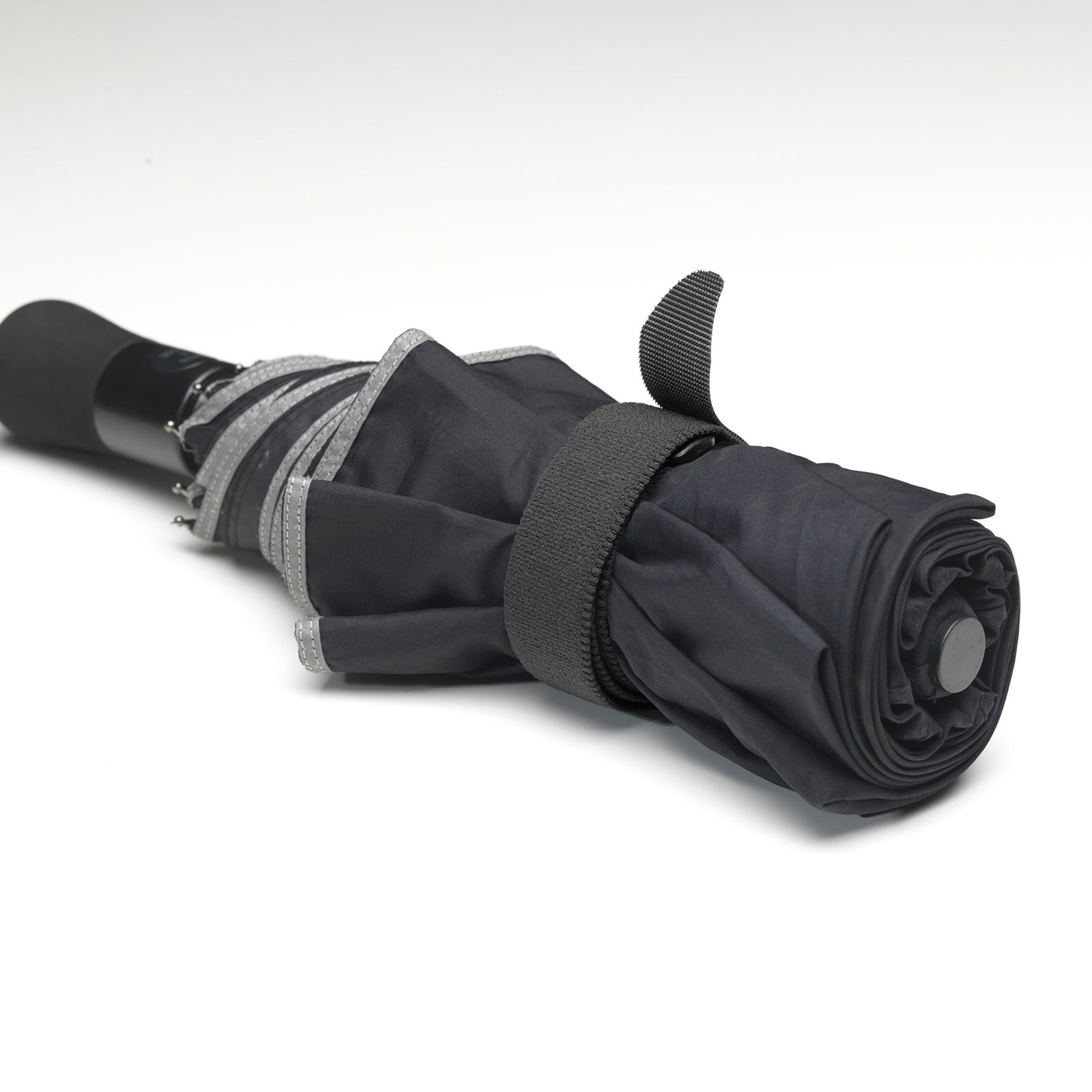 Rolled black umbrella secured neatly with a reusable VELCRO Brand adjustable strap demonstrating strong fastening and organised storage capability.