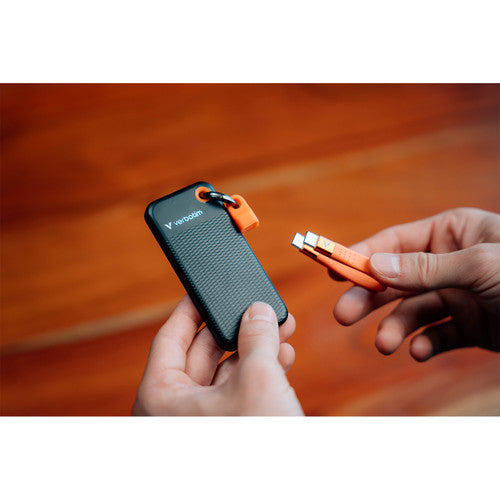 Two hands holding the Verbatim Pocket SSD and unclipping the orange USB-C cable from its keyring