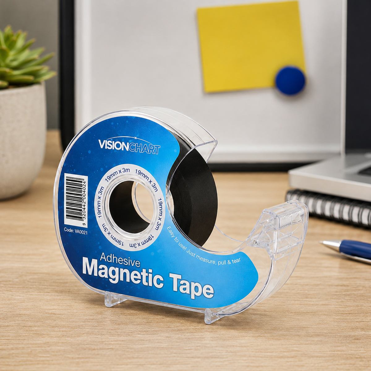 The Visionchart Magnetic Tape Dispenser sits on an organised office desk beside a laptop, notebook and whiteboard. The clear dispenser showcases the 19 mm by 3 metre black magnetic tape, highlighting its convenient desktop storage.