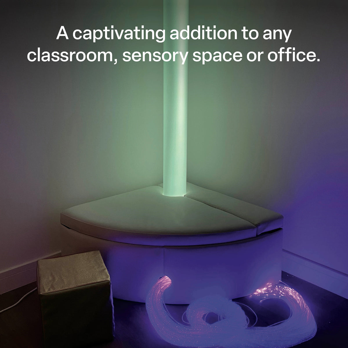 Waterless LED sensory tube installed in a sensory environment with soft surrounding equipment and fibre optic resources. The illuminated tube creates a gentle green glow across the nearby walls, demonstrating how the tall light feature can become a visually captivating addition to classrooms, sensory spaces and other supervised indoor environments.