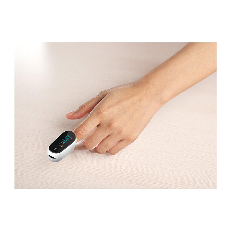 Hand resting on a table with the Wellcare fingertip pulse oximeter clipped onto the index finger