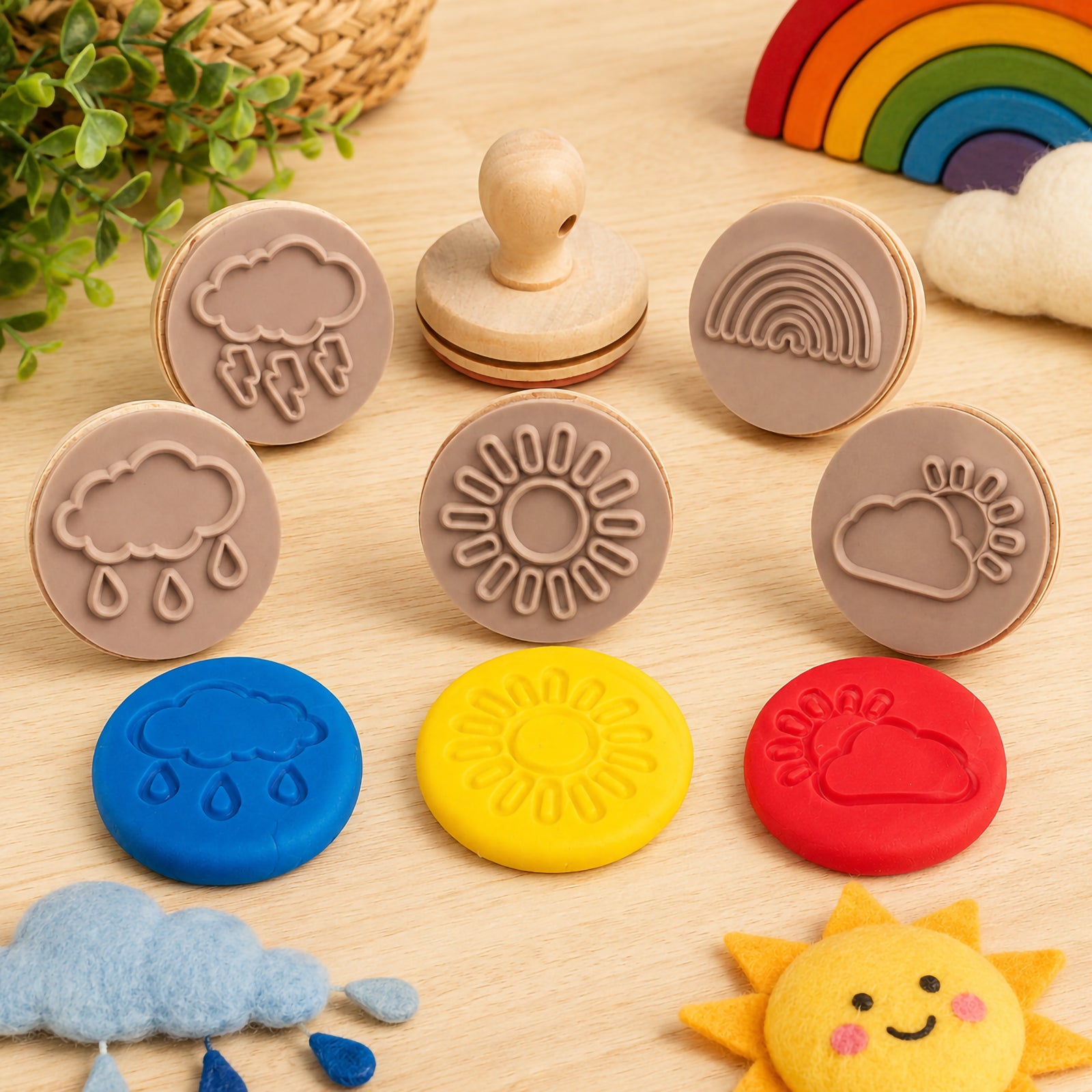 Wooden weather dough stamps displayed with colourful dough impressions featuring rain clouds, sunshine, rainbow and storm cloud designs. The sensory play setup includes soft decorative weather themed props, encouraging imaginative learning and tactile exploration for young children.
