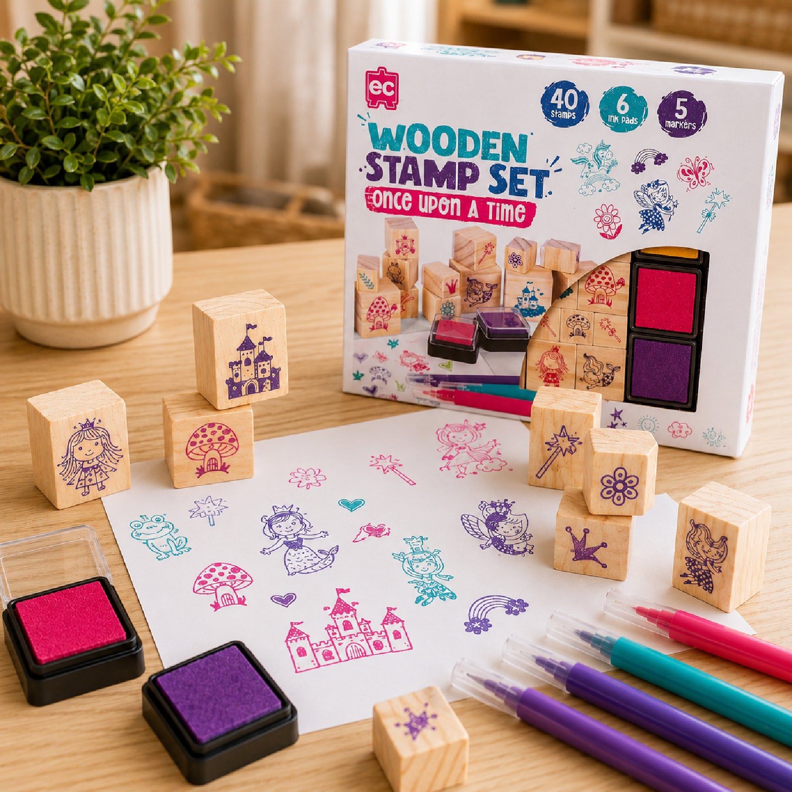 Educational Colours Wooden Stamp Set Once Upon A Time retail packaging displayed with fairytale themed stamps, colourful artwork examples, ink pads, and markers arranged on a classroom style table for creative learning.