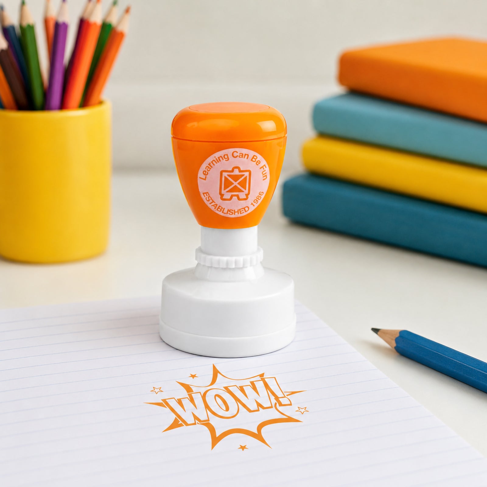 Self inking Wow Merit Stamp presented with colourful books and pencils in a classroom setting. The eye catching design and bright orange impression showcase an effective reward tool for encouraging positive learning outcomes.