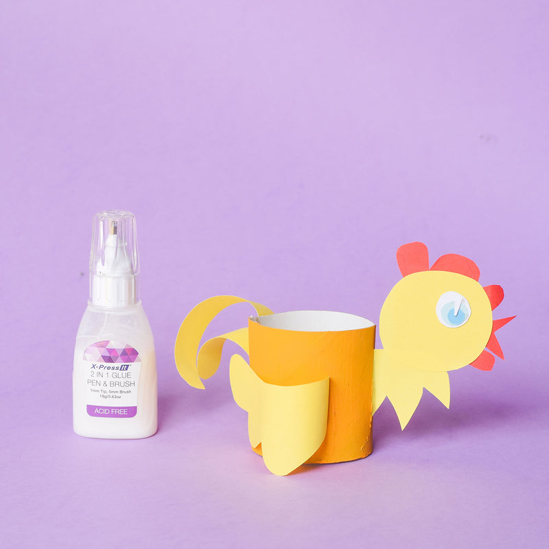 X-Press It 2 in 1 Glue Pen and Brush bottle beside a yellow paper chicken craft on a lilac background