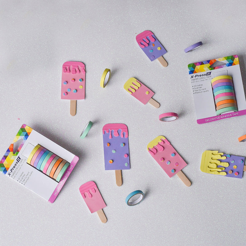 Paper ice block shapes decorated with pastel tape on a grey surface, with two X-Press It deco tape packs and loose rolls