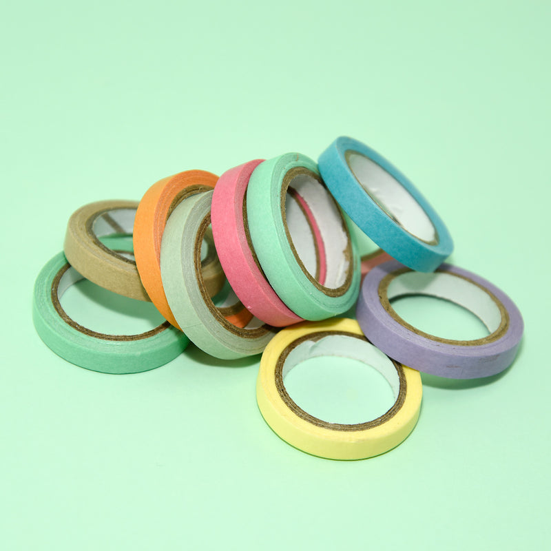 Loose pile of slim pastel deco tape rolls on a mint green background