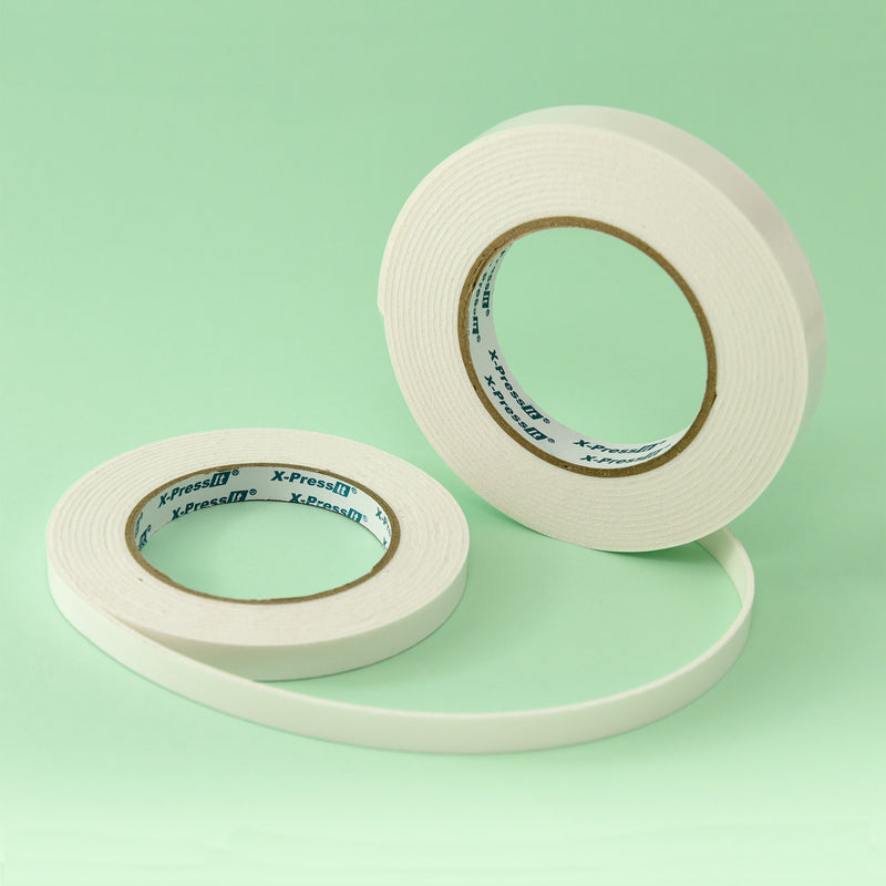 Two white X-Press It foam mounting tape rolls in different widths on a mint green background
