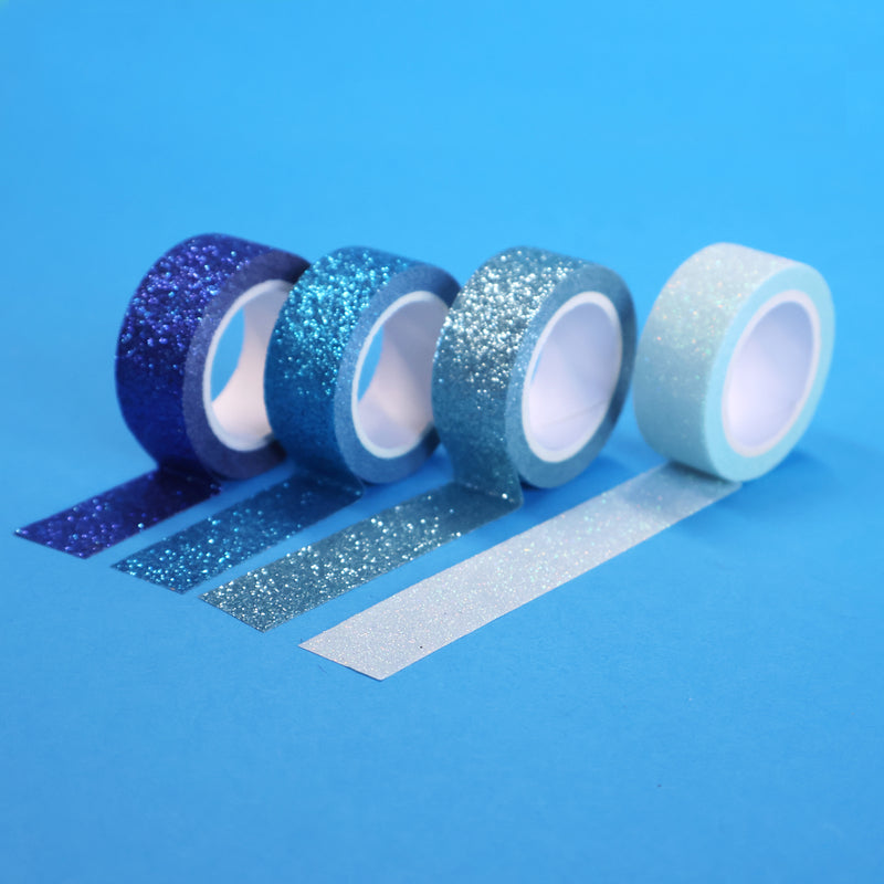 Four X-Press It blue glitter tape rolls from royal blue to pale aqua with strips unrolled on blue