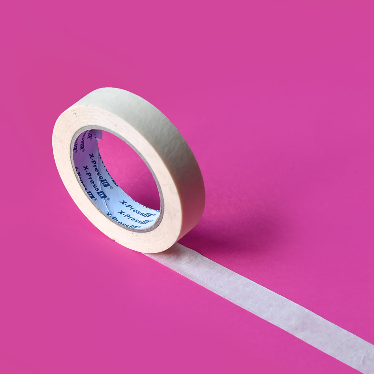Cream masking tape roll with X-Press It printed core and a strip unrolled across a magenta surface