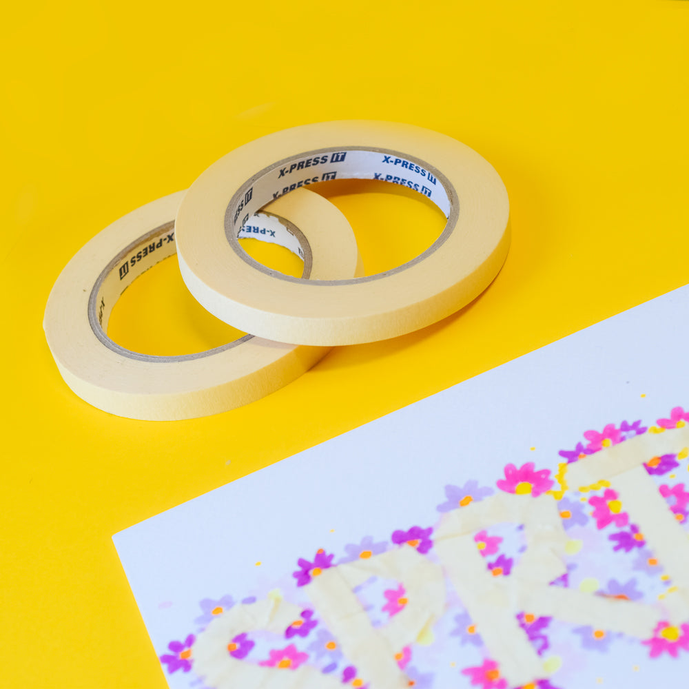 Two masking tape rolls with printed X-Press It cores on yellow beside a flower print with lettering masked out