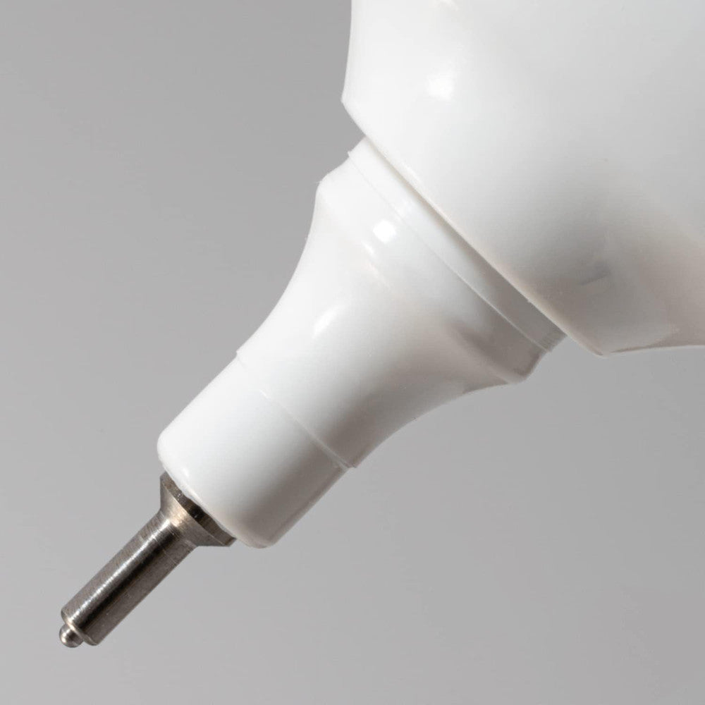 Close-up of the white nozzle and metal tip of a Pentel fine point correction pen against a grey background