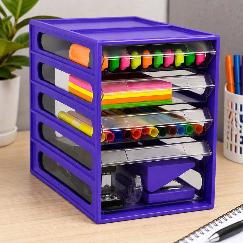 Angled lifestyle view of the Italplast 4 Drawer Office Organiser in Grape positioned on a modern desk. Clear drawers display bright stationery including highlighters, sticky notes and coloured writing tools, with larger office equipment stored below. The compact upright design demonstrates efficient organisation for office, classroom or study environments.