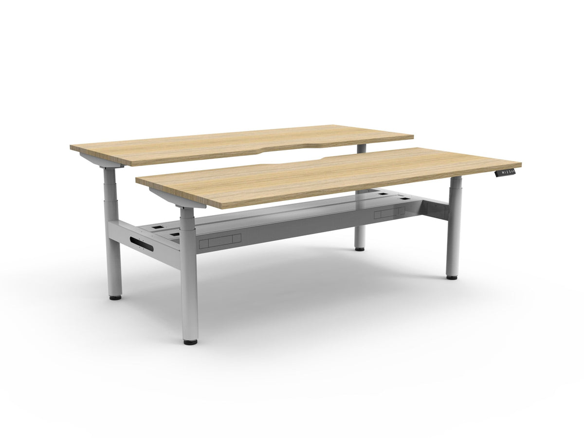 Rapidline Halo Plus electric height adjustable back to back workstation on 70mm diameter round columns, E0 rated Natural Oak top with a white satin powdercoated frame, fitted ducted cable tray. Rapidline range image supplied for model H+2PCT1275 NO/WS.