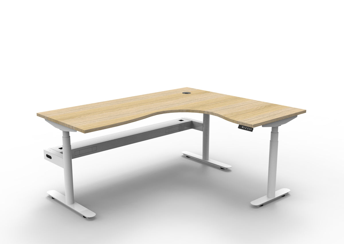 Rapidline Halo Plus electric height adjustable corner workstation on 70mm diameter round columns, E0 rated Natural Oak top with a white satin powdercoated frame, fitted ducted cable tray. Supplied product image for model H+CNRCT1P1815 NO/WS.