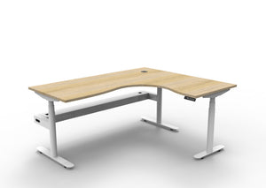 Rapidline Halo Plus electric height adjustable corner workstation on 70mm diameter round columns, E0 rated Natural Oak top with a white satin powdercoated frame, fitted ducted cable tray. Supplied product image for model H+CNRCT1P1815 NO/WS.
