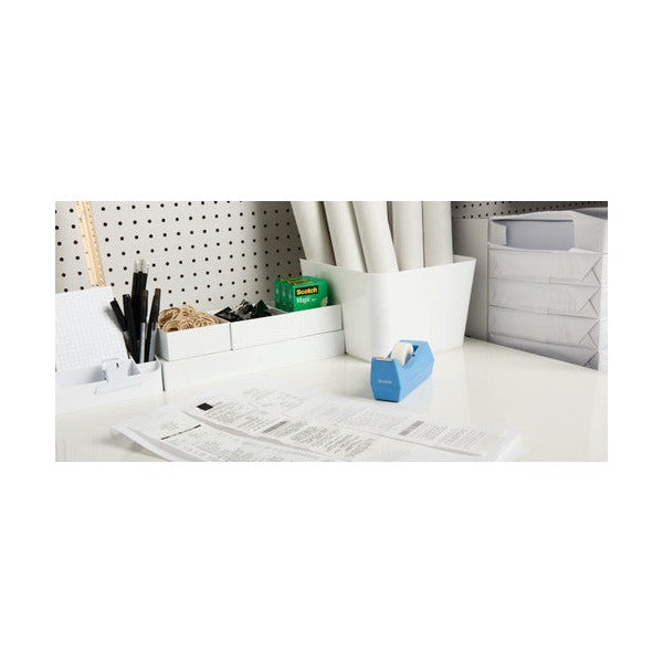 Tidy white desk with a pegboard, pen pots, paperwork and a blue Scotch desktop tape dispenser holding a roll of tape